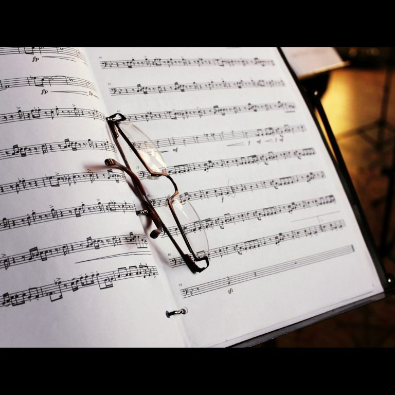 Notenblatt mit Musiknoten und einer Brille, die auf der Seite liegt.