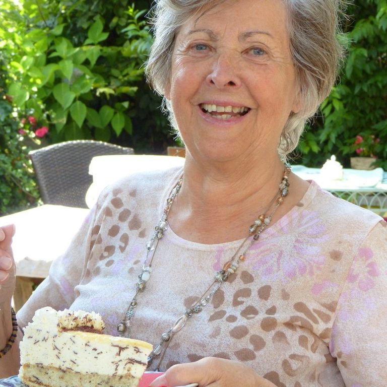 Rosa Blüten wachsen an einem weißen Fußgängergeländer.