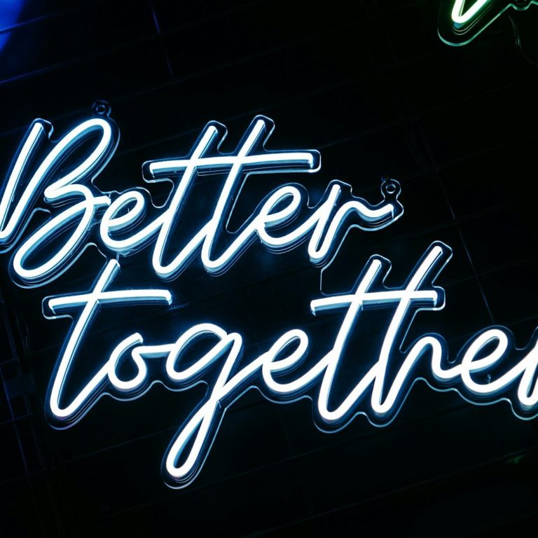 Eine Hand hält ein glühendes Wunderkerze zwischen grünen Blättern.