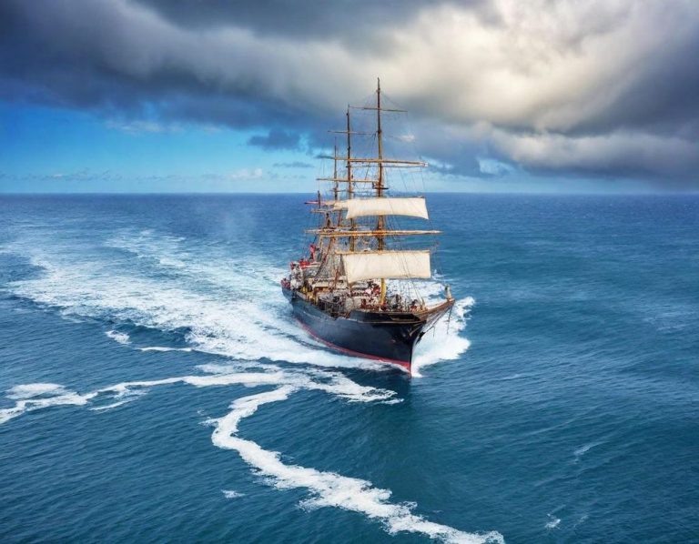 Traditionelles Segelschiff mit roten und blauen Segeln auf ruhigem Wasser.