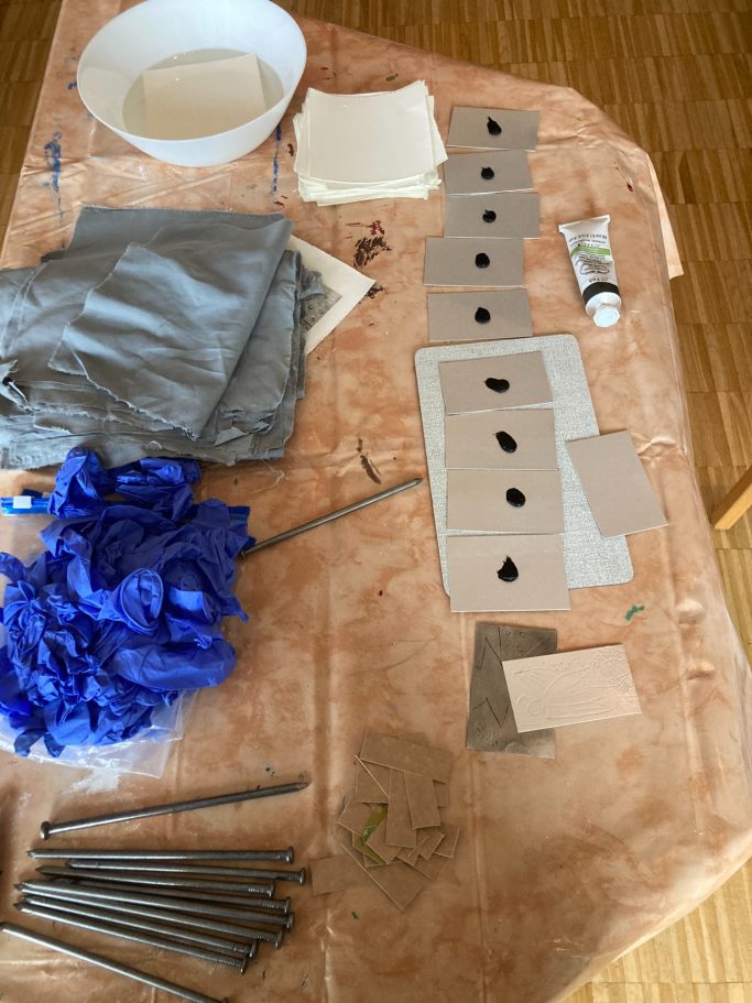 Werkzeug und Materialien zum Basteln: Stoffe, Pappe, Farbe und Werkzeug angeordnet.